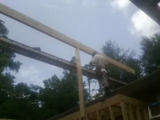 Carpenter setting a ridge beam over a new addition frame — Ice Dam Removal by Roofing Brothers in Falkland