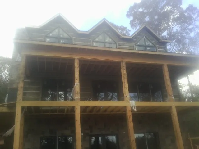 Dormers and porch framing on a large log home under construction — Roof Coating work by our crew in Falkland