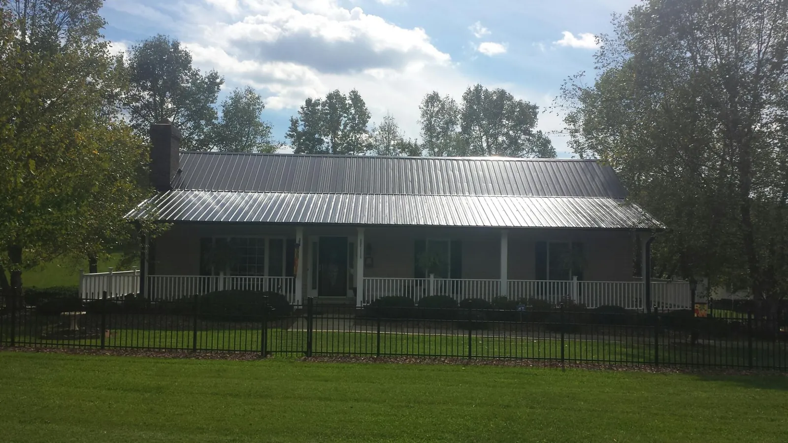 Gray metal roof on a brick ranch with a full width front porch — Gutter Guard Installation work by our crew in Falkland