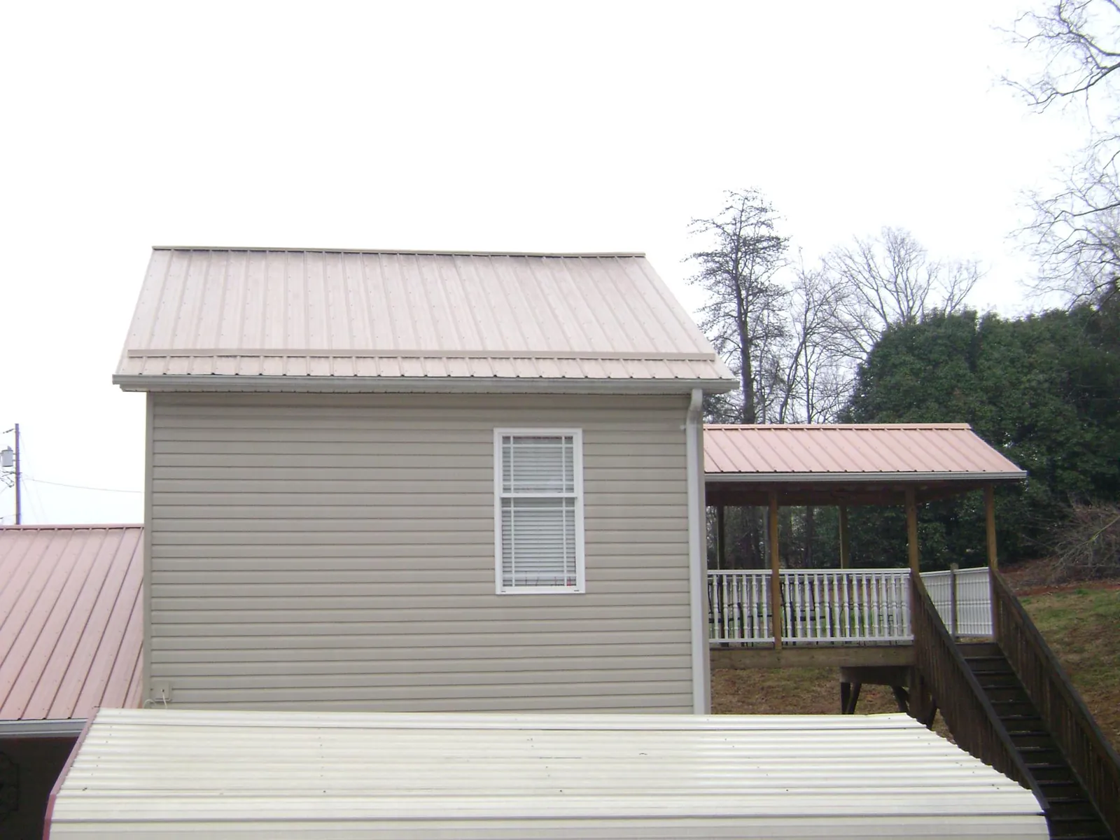 Tan metal roofs on a two story addition and attached porch, from a Roof Replacement job in Falkland