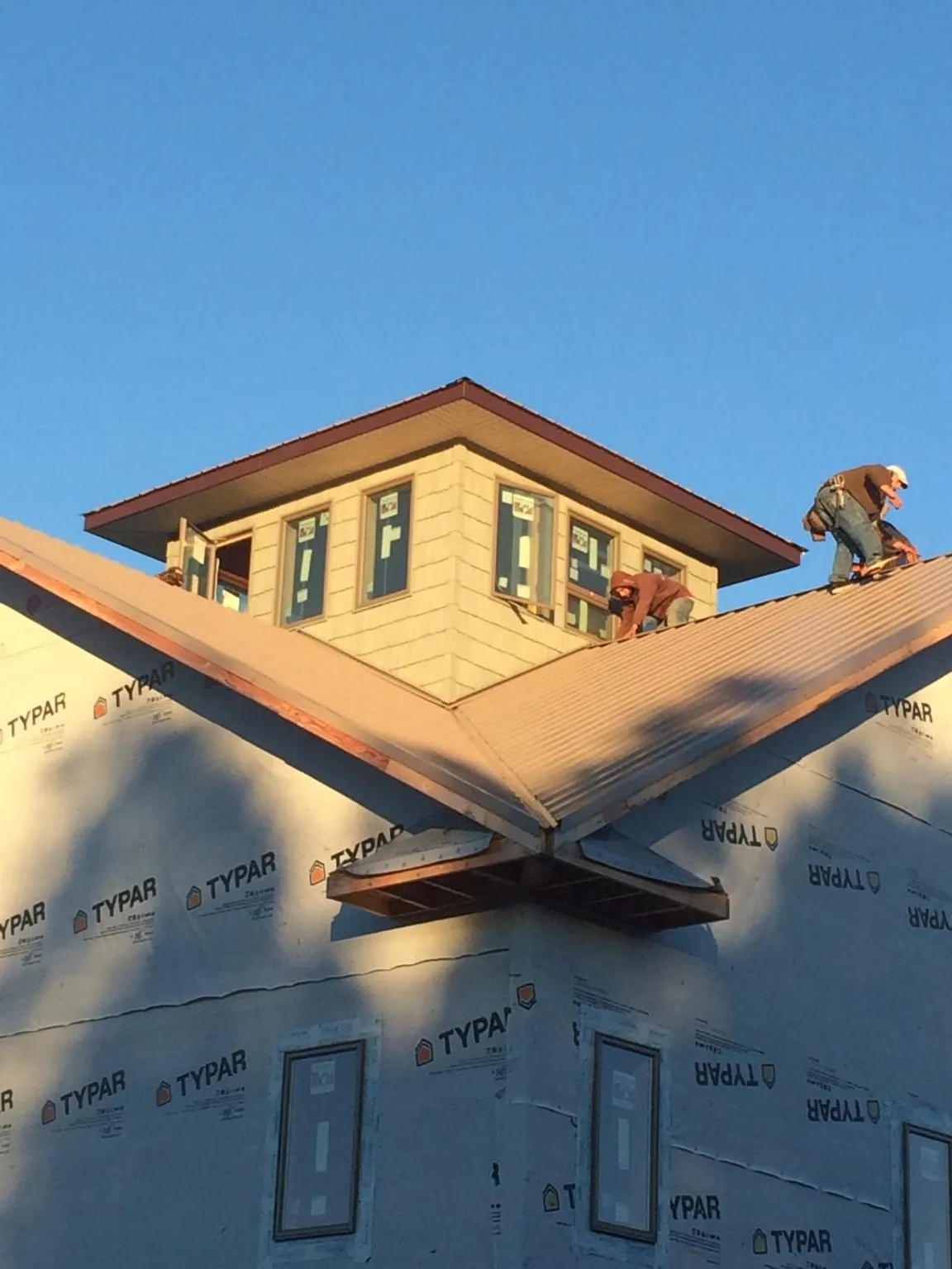 Roofers working around a rooftop cupola on a new metal roof at sunset — Roof Waterproofing in Falkland by Roofing Brothers